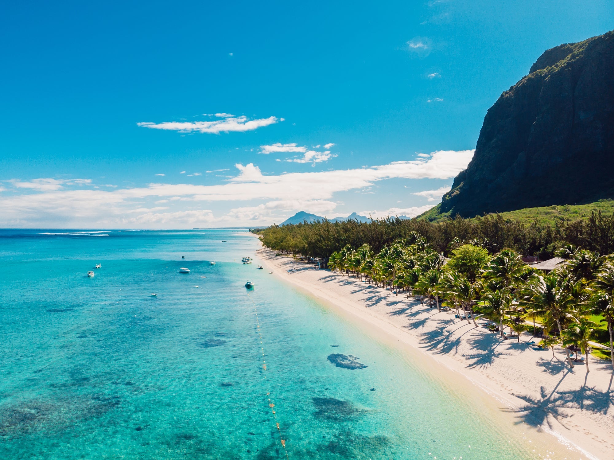 Luxury beach with mountain in Mauritius. Sandy beach with palms and blue ocean. Aerial view (Photo by Nuture/Getty Images)