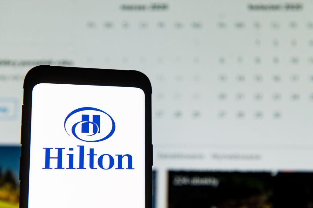 In this photo illustration a Hilton logo seen displayed on a