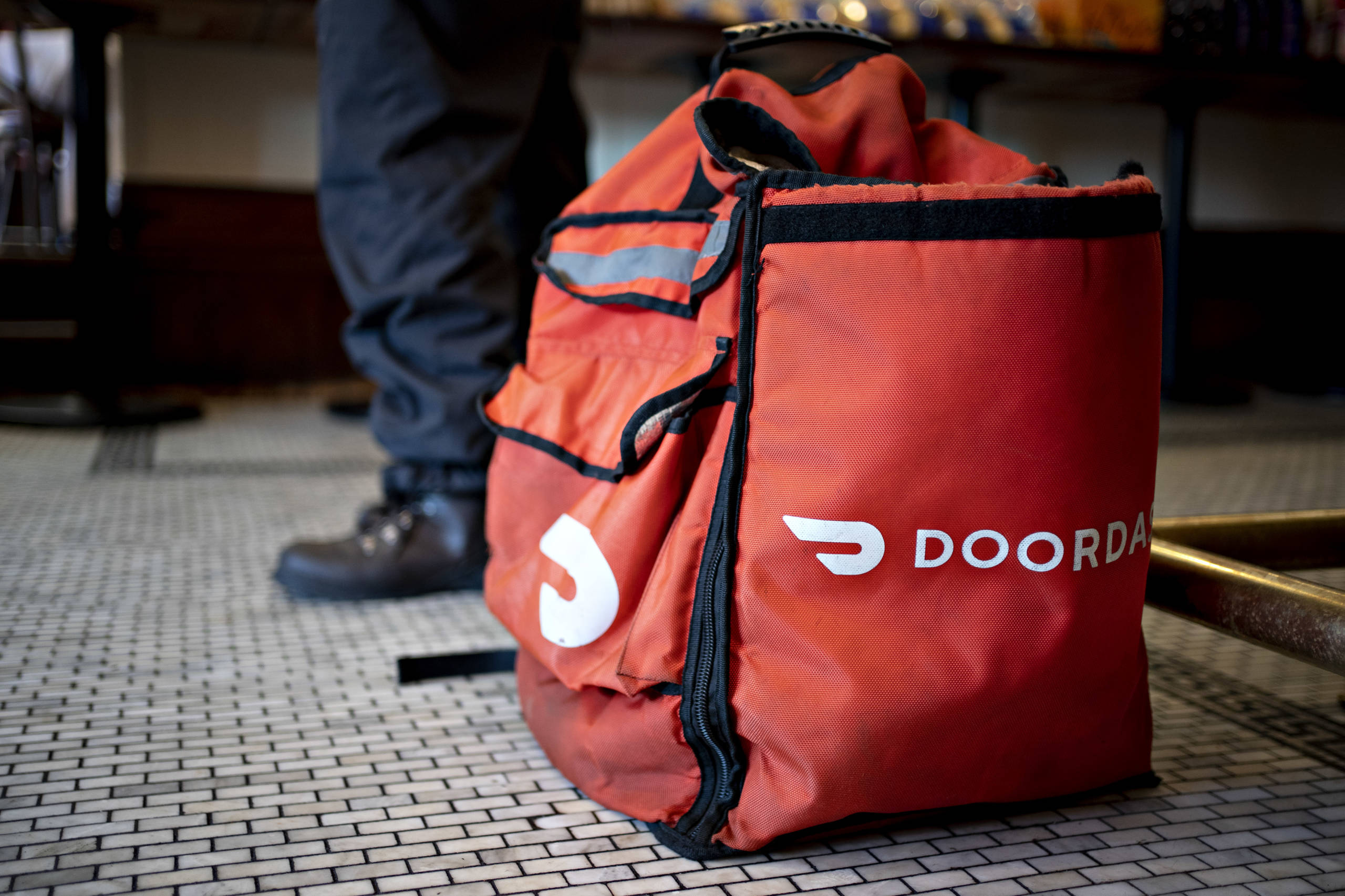 A DoorDash Inc. delivery bag sits on the floor at Chef Geoff's restaurant in Washington, D.C., U.S., on Thursday, March 26, 2020. As the wheels of government turn too slowly for small businesses desperate for a piece of the $2 trillion U.S. relief package due to the coronavirus pandemic, restaurateur Geoff Tracy is using GoFundMe to raise money for 150 hourly workers at his American comfort food standby Chef Geoff's and other restaurants. Photographer: Andrew Harrer/Bloomberg via Getty Images