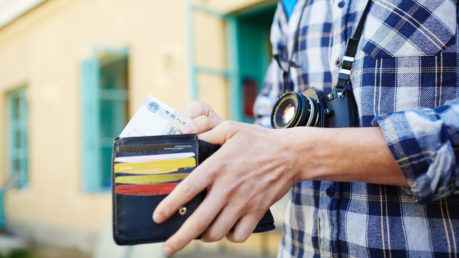 Closeup image of young tourist putting money in wallet, saving money for vacation trips
