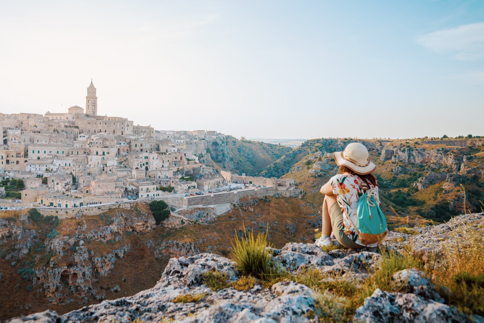 Young Woman tourist with hat admiring the view of Matera at sunset