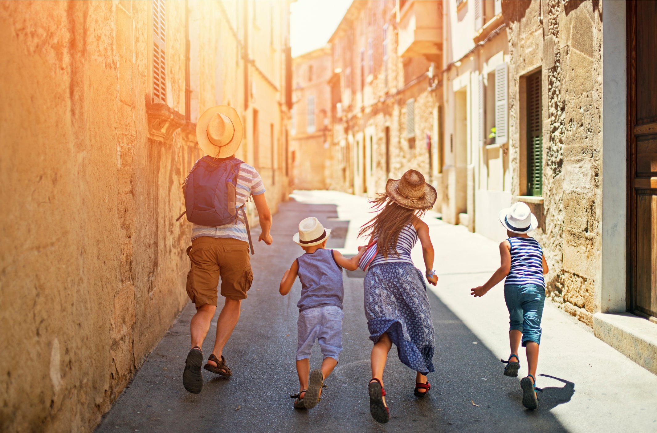 A family of four running through a quiet street in Europe.