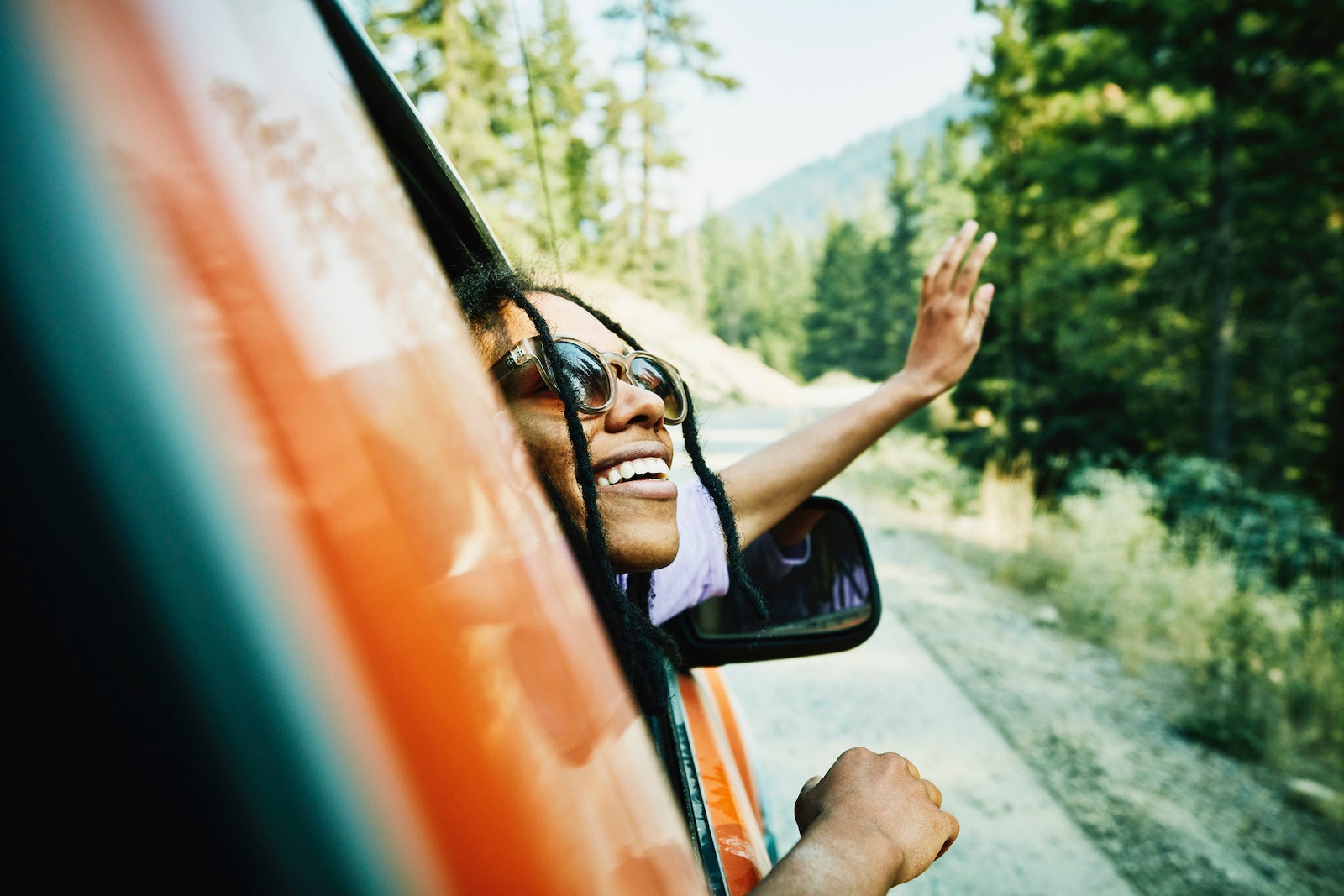 a person leans out the window of a car while smiling