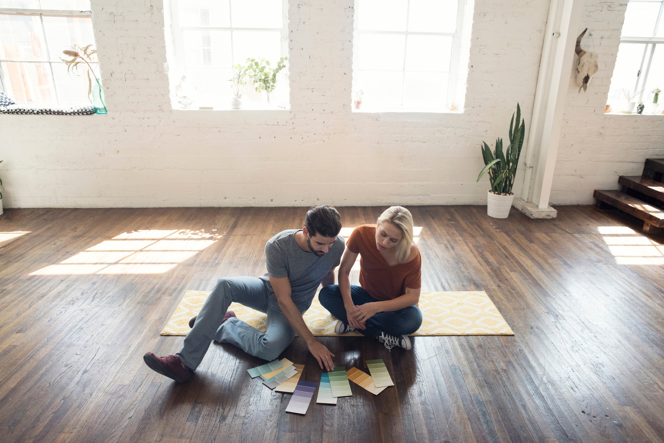 Young couple sitting on carpet in a loft looking at color samples
