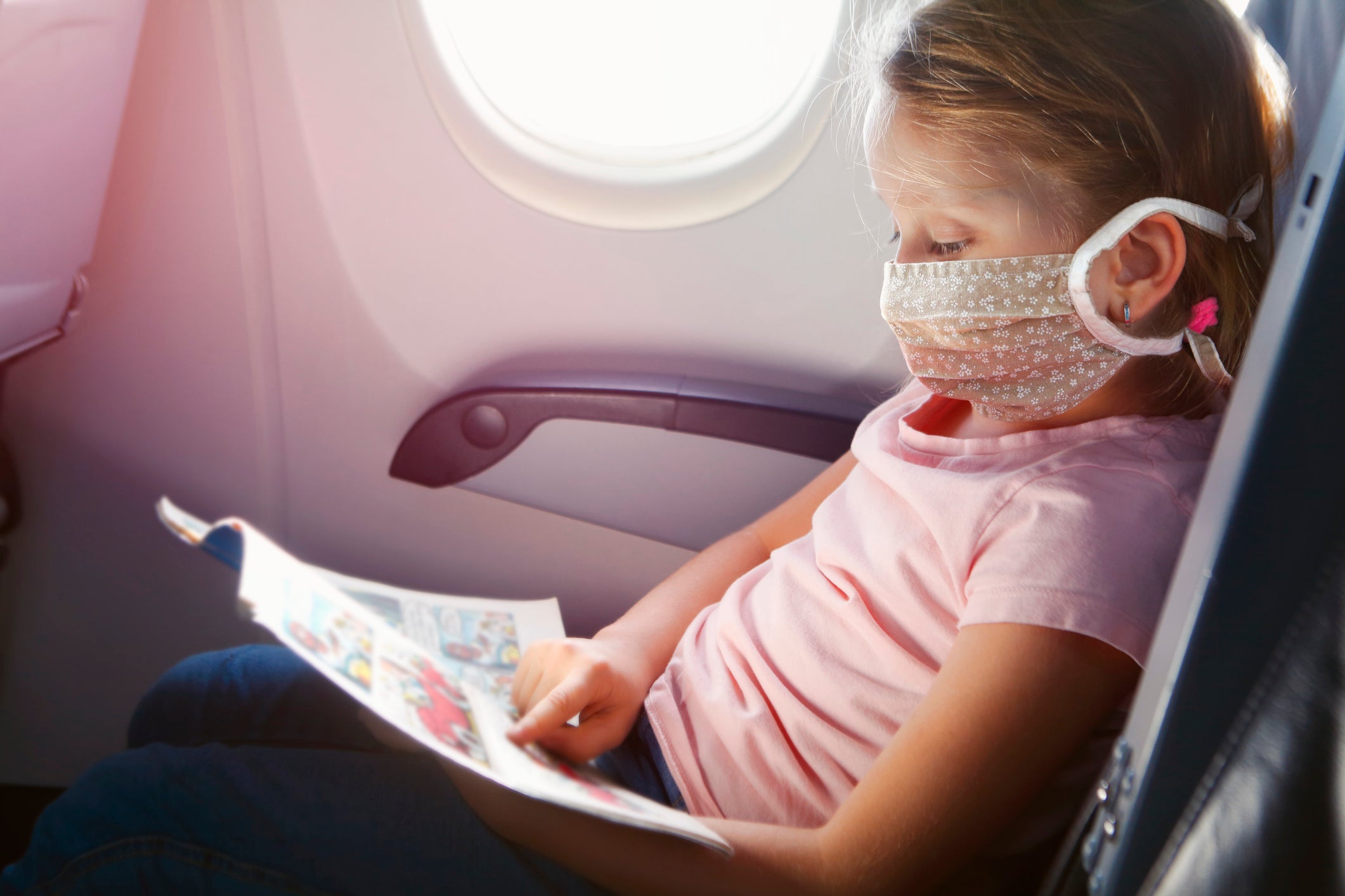 Girl with face mask flying by airplane