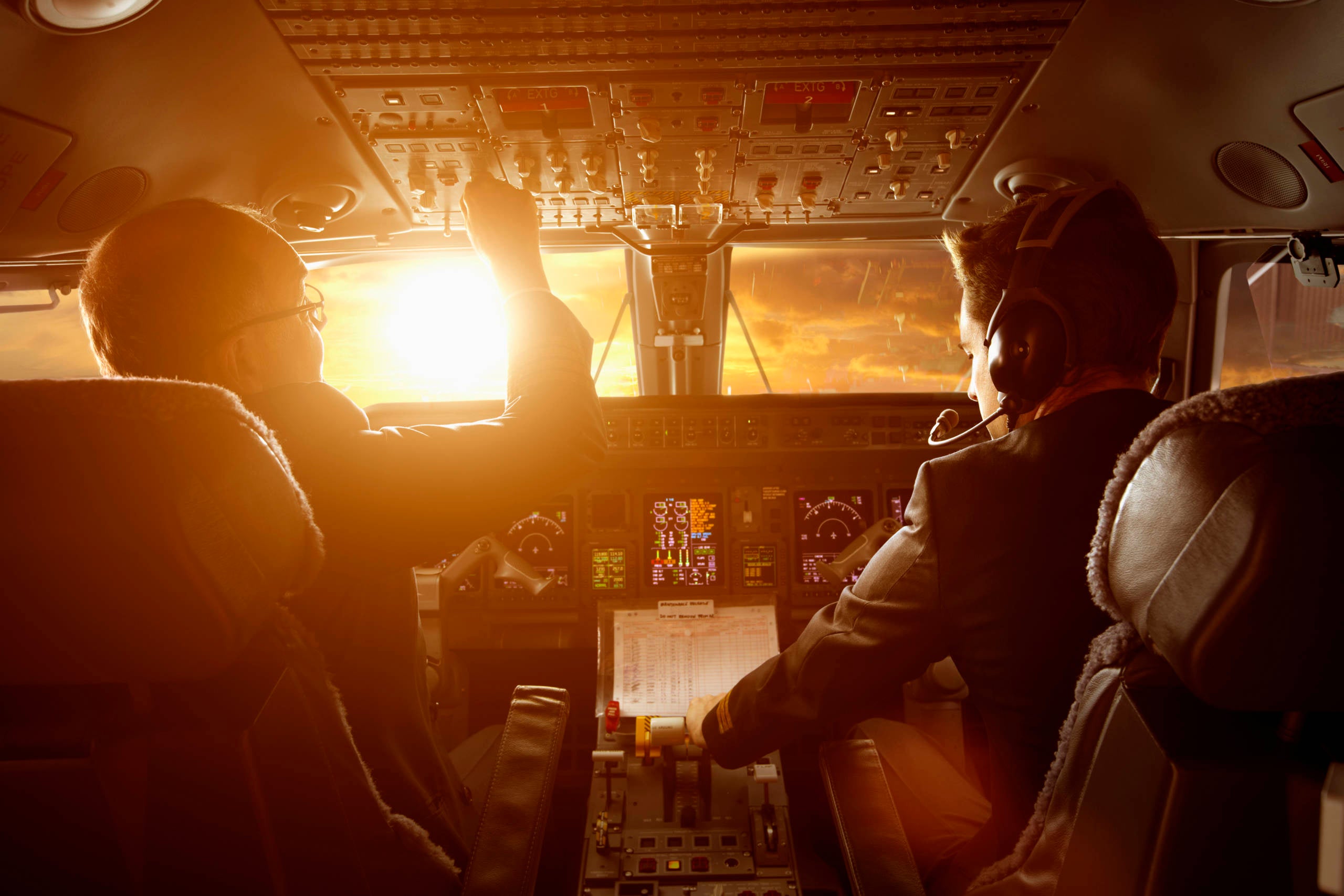 Caucasian pilots flying jet at sunset