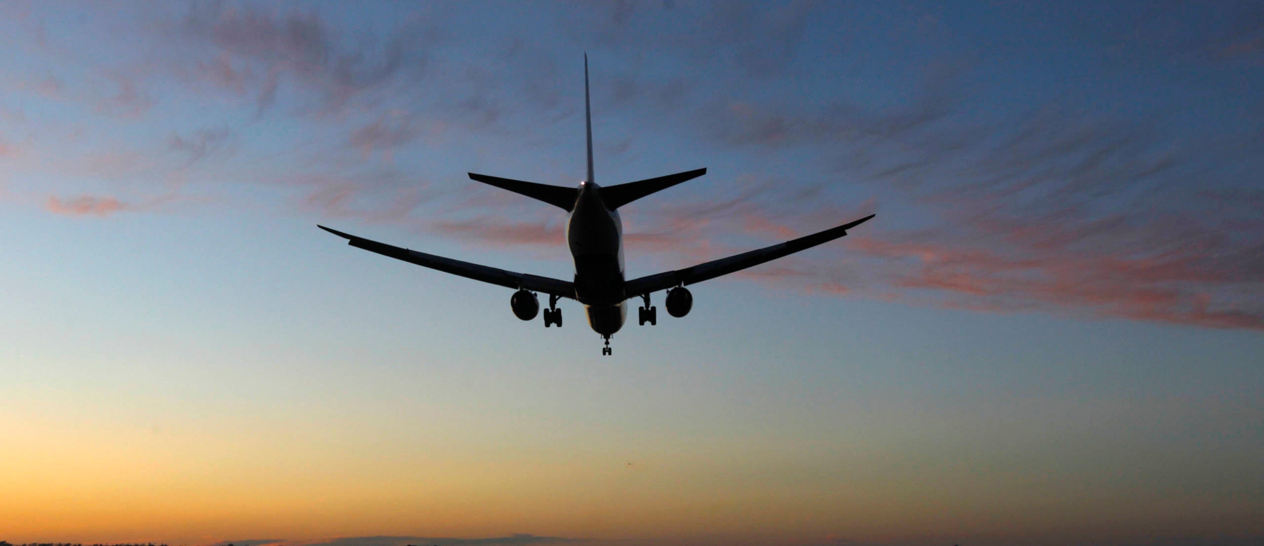 A 787 jet airplane lands at San Diego International Airport at sunset.