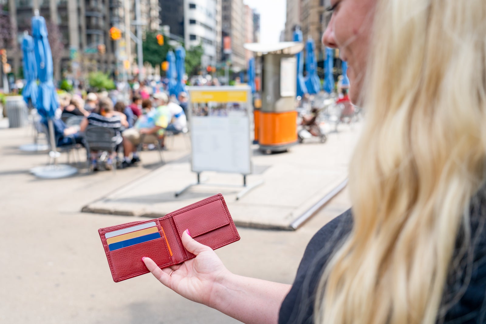 Woman on city street looking at wallet