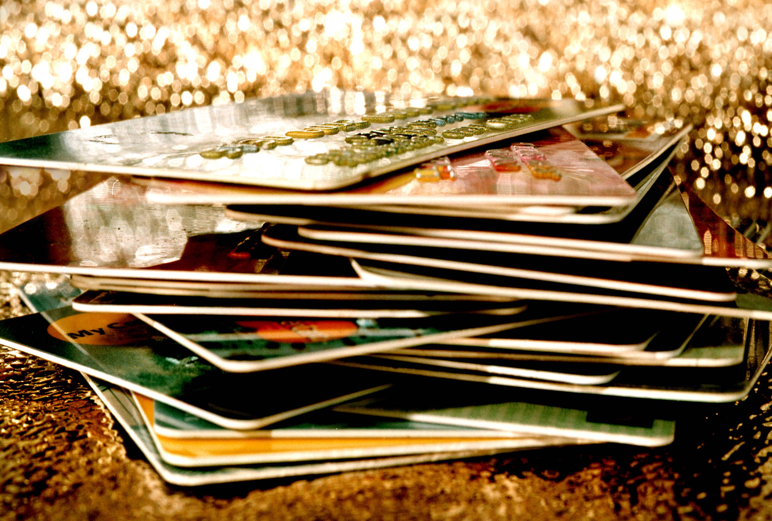 photo shows a large stack of credit cards in a pile against a gold, bedazzled background