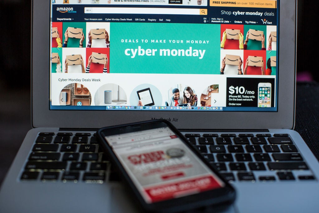 A laptop screen shows the words Cyber Monday with multiple shopping deals