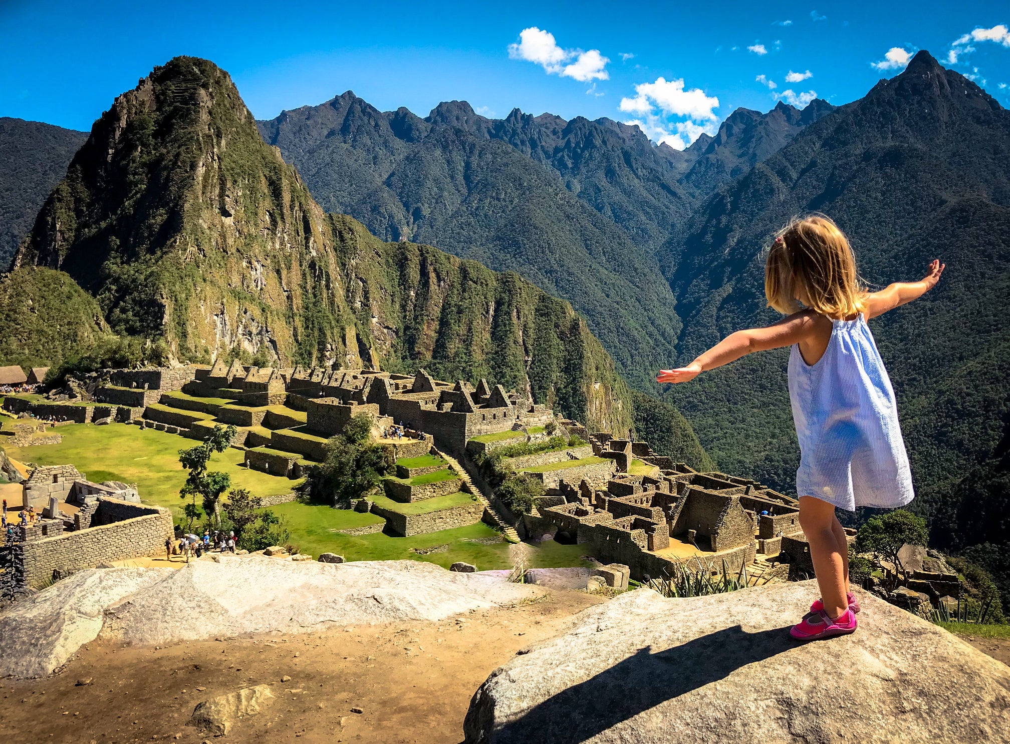 Full Length Of Girl Standing With Arms Outstretched On Rock At Mountain