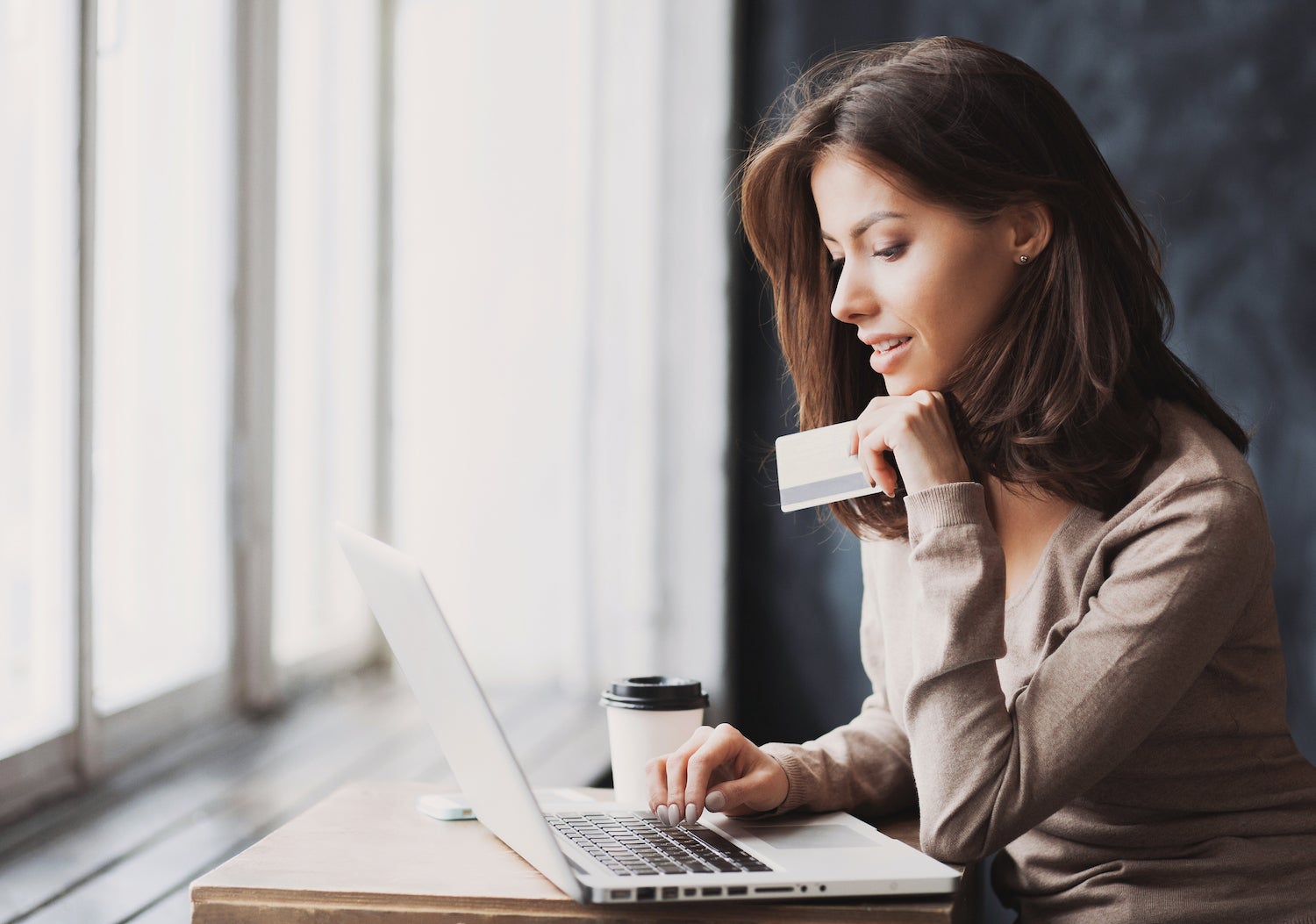 Woman Holding Credit Card in Front of Laptop