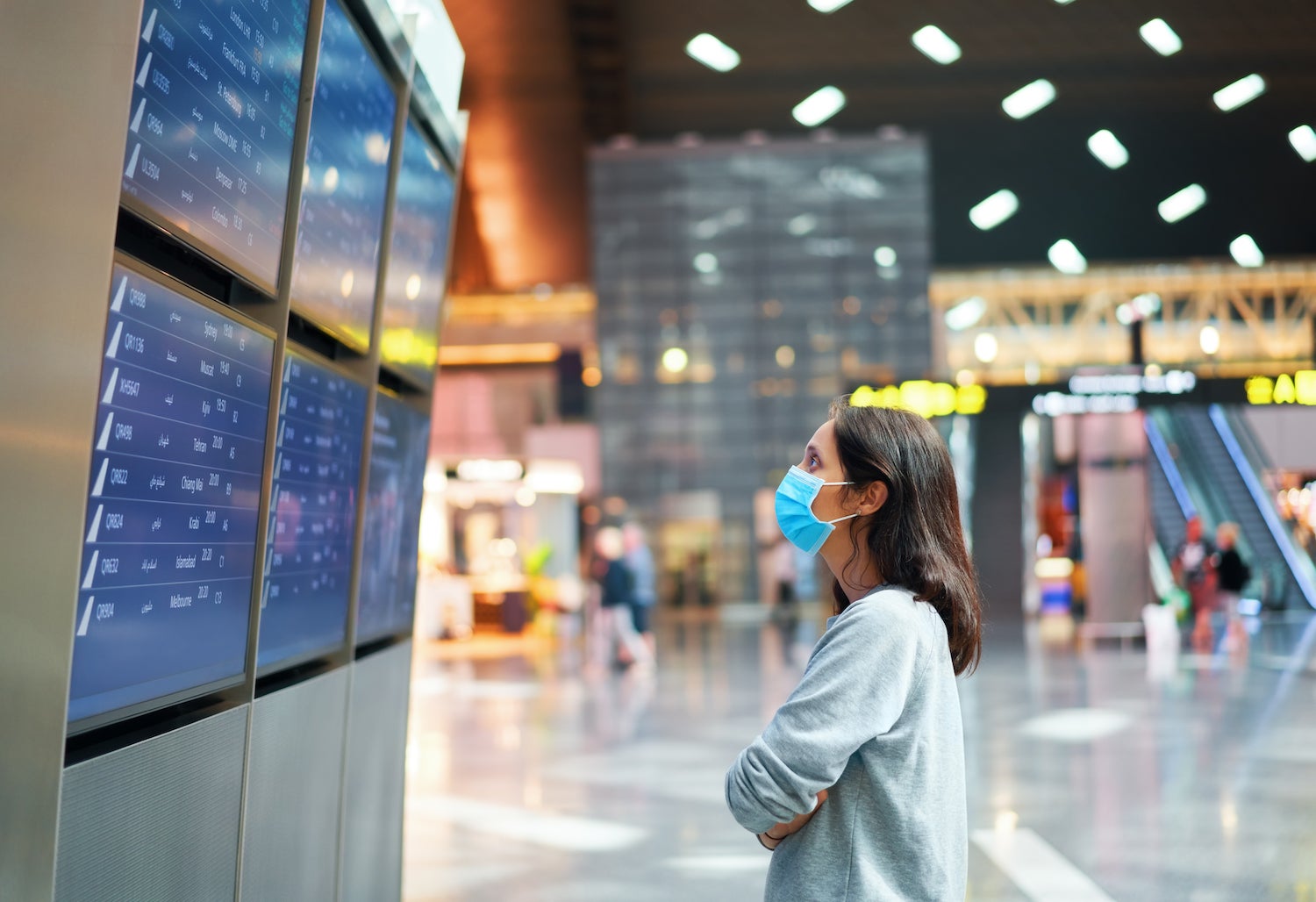 Woman Looking at Flight Departure While Wearng a Mask