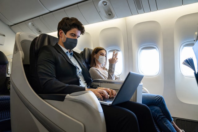 People traveling by air in business class and wearing facemasks on the plane