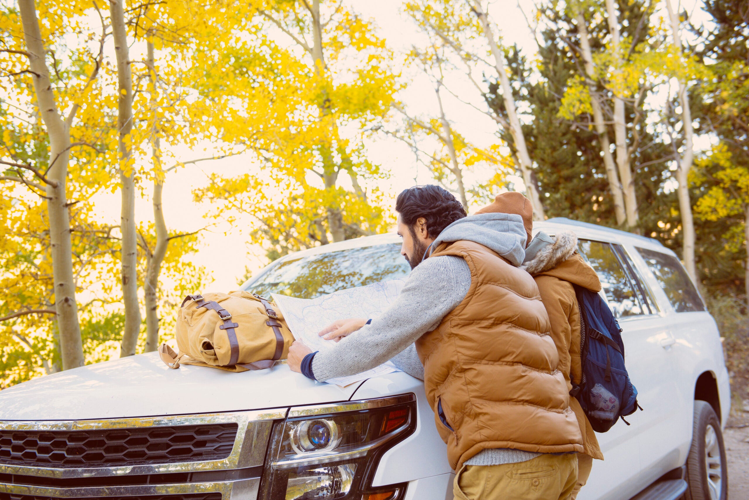 hikers leaning on SUV hood reading map