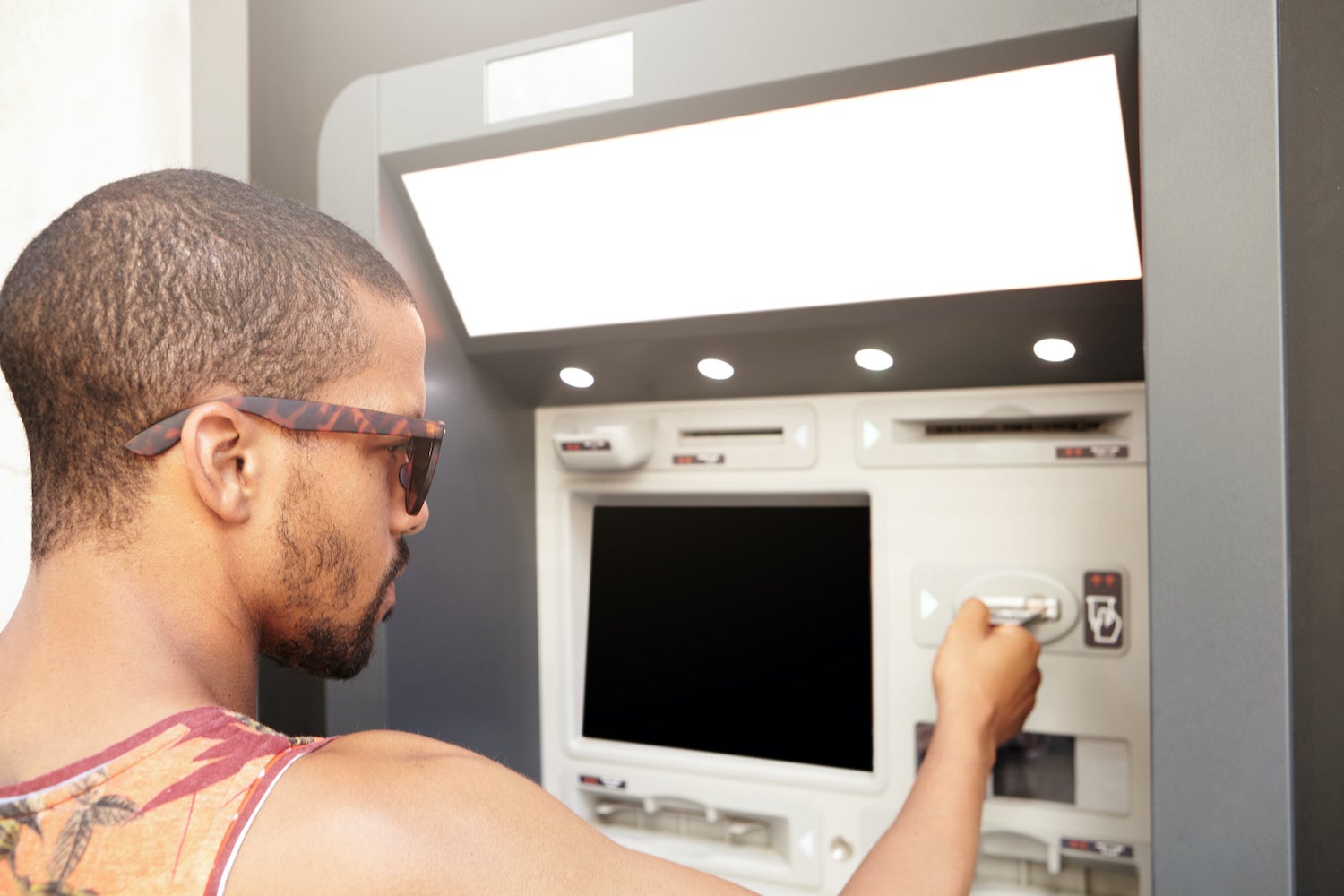 Man in sunglasses using an ATM