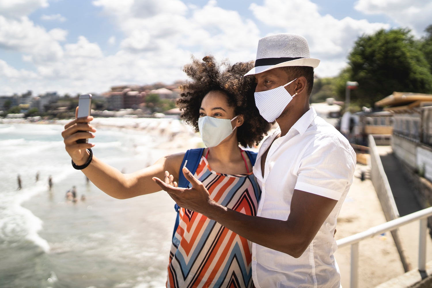 Couple taking selfie on beach with masks on