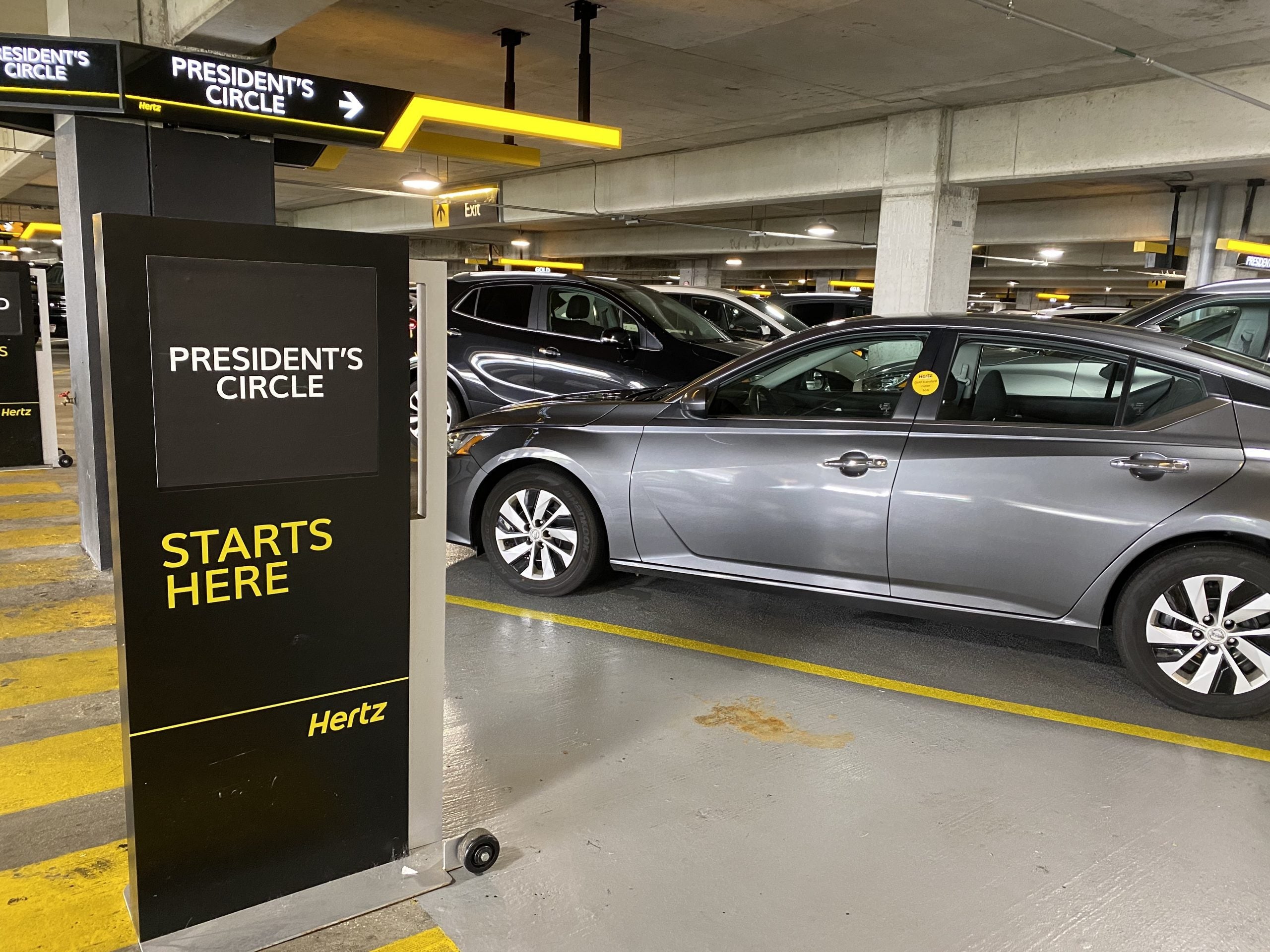 Photo of a sign saying 'president's circle starts here' in a Hertz car rental lot