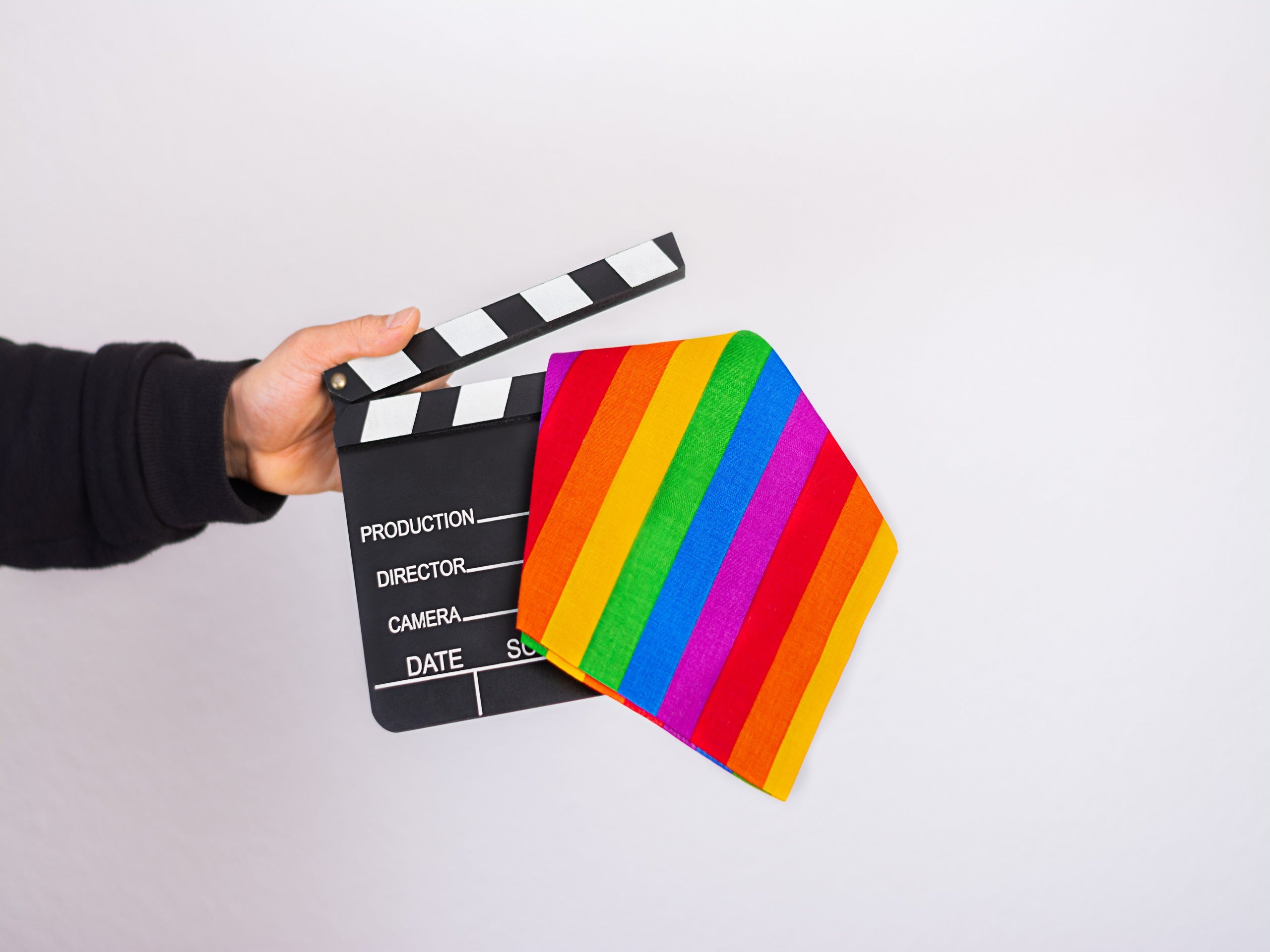 A man hand holding a Lgbt rainbow flag and movie clapper board