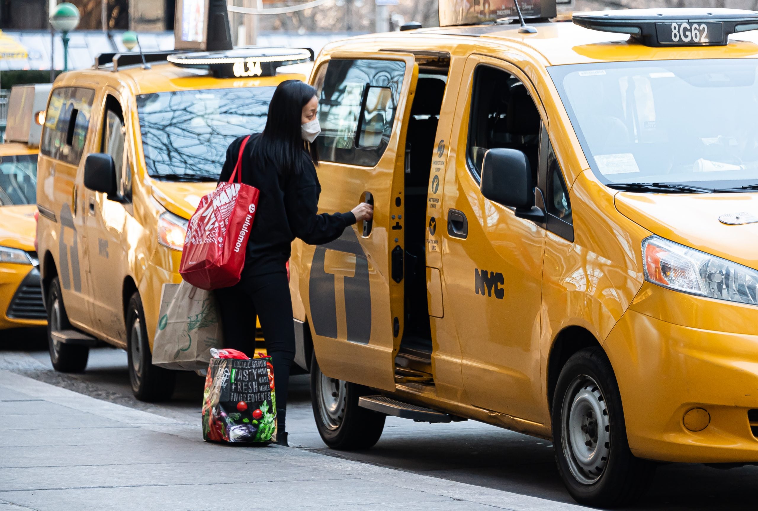 A person in a face mask gets into a taxi in New York