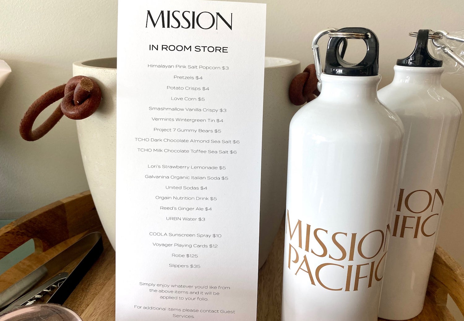 In-room hotel snack menu next to two branded water bottles