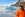 Man wearing orange hat and jacket looks to the side with glacier in the background.