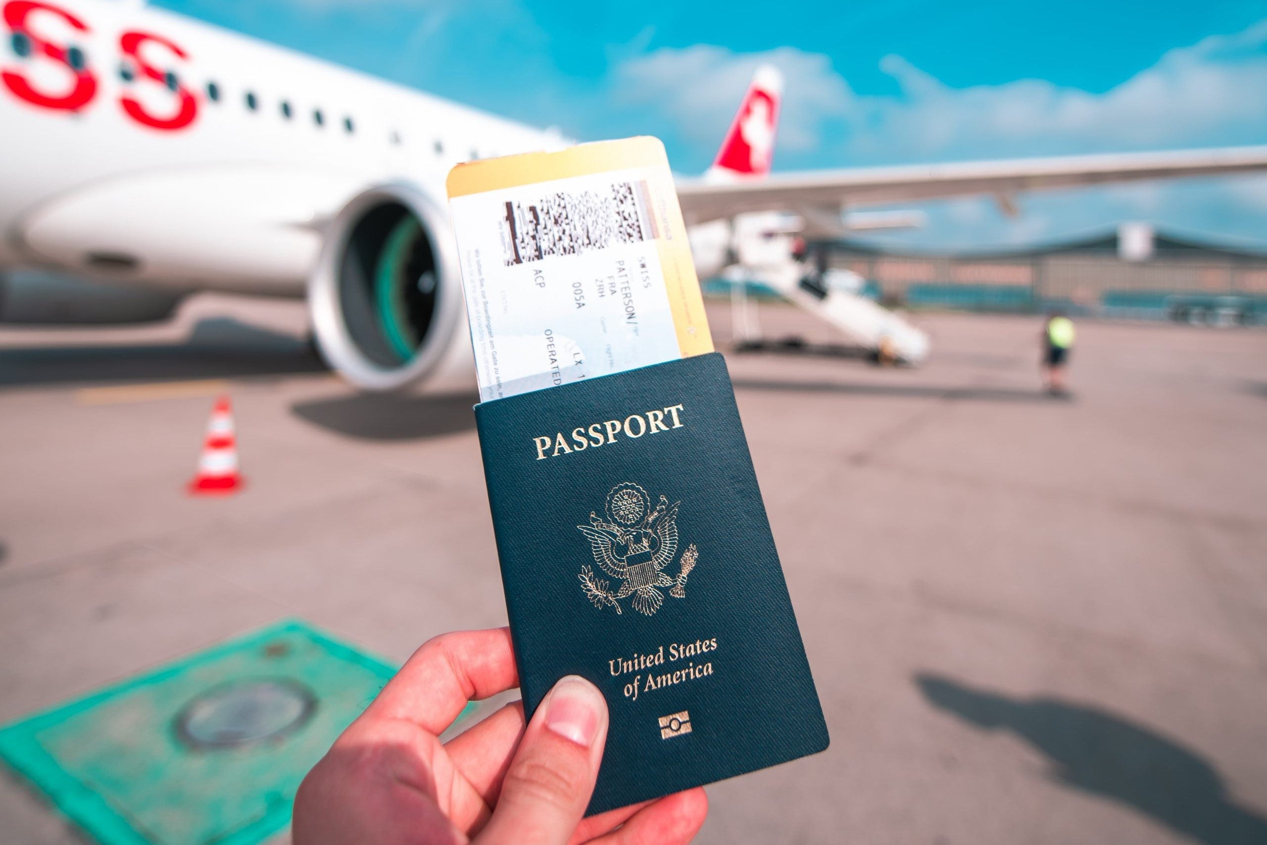 Hand holding a US passport outside a Swiss plane