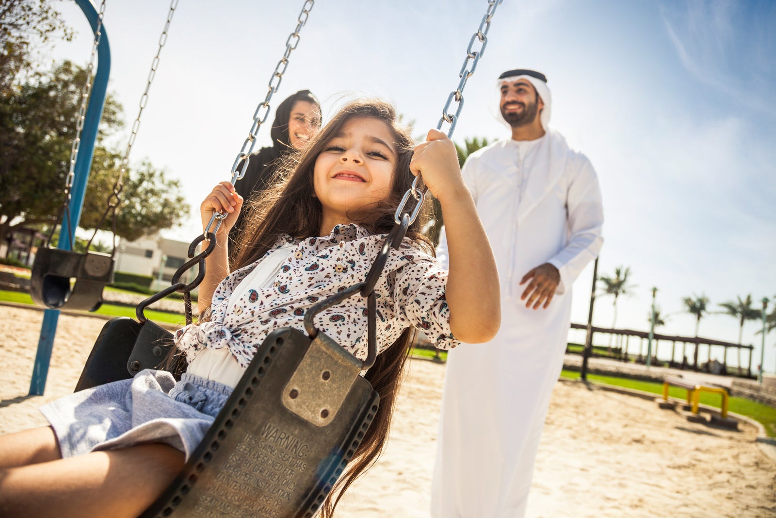 Parents push a child on a swing