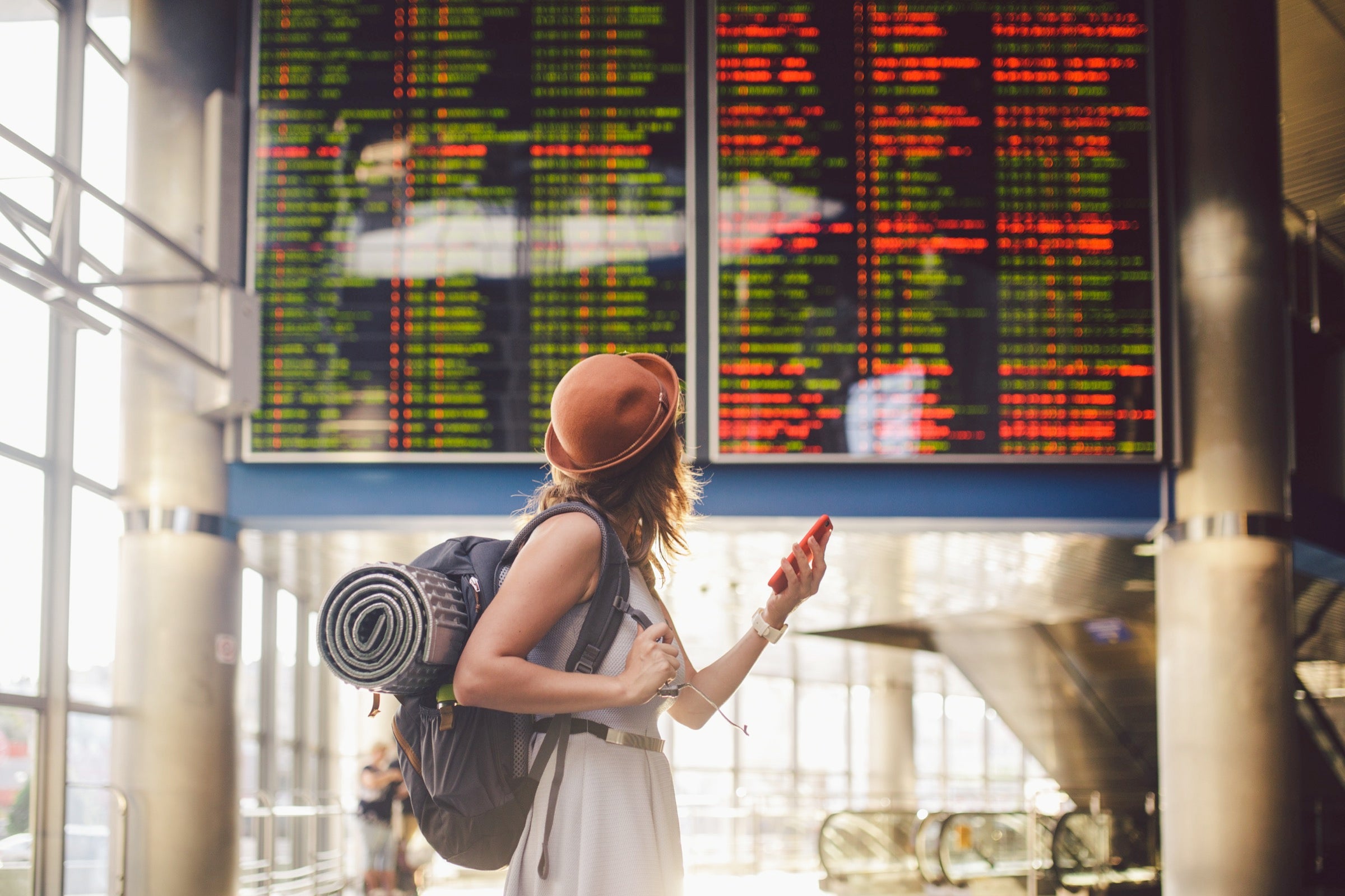 Female solo traveler in front of a flight board at an airport