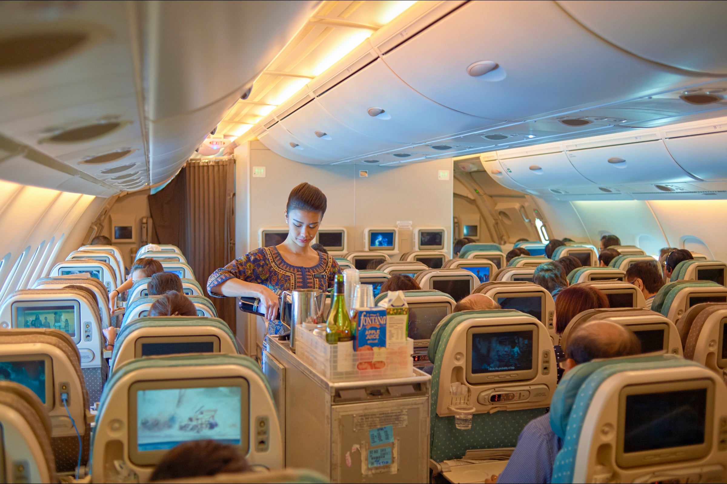 Flight attendant serving drinks from airplane bar cart