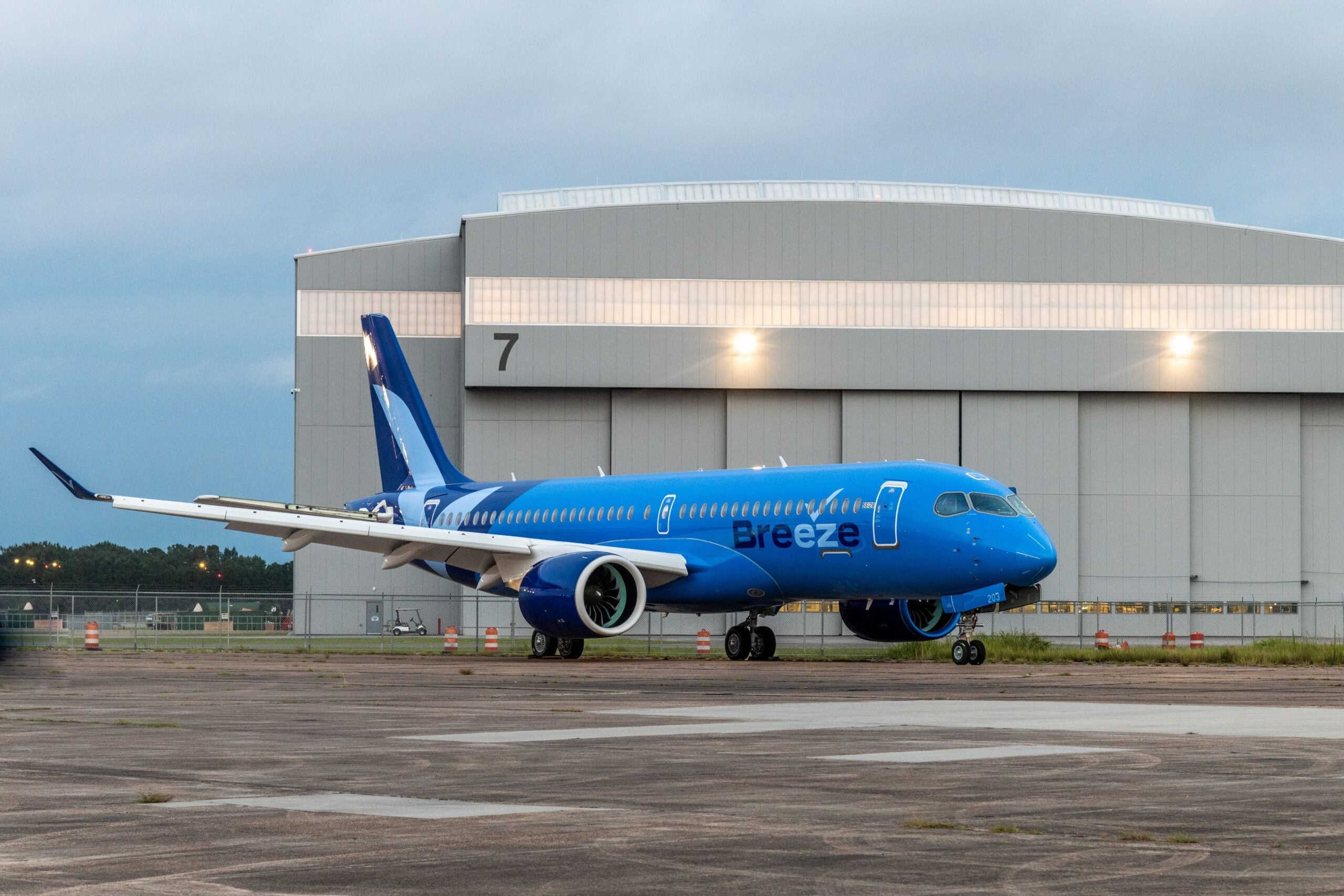 An Airbus A220 plane painted in Breeze Airways livery sits in front of the paint shop at Airbus' facility in Mobile, Alabama