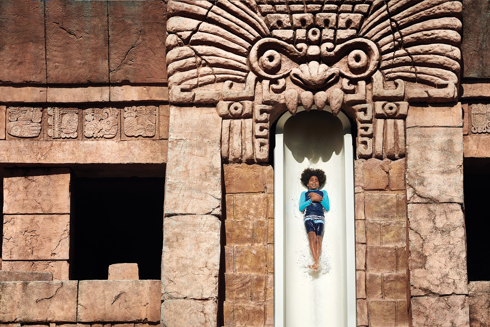 Young boy going down a steep waterslide at Atlantis