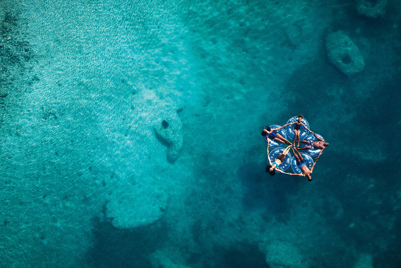 Family of 5 enjoying a relaxing while laying on a tube in the ocean. Blue green water surrounds them.