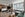 large hotel room with green couch, tv on bookshelf, bed, and views of New York City