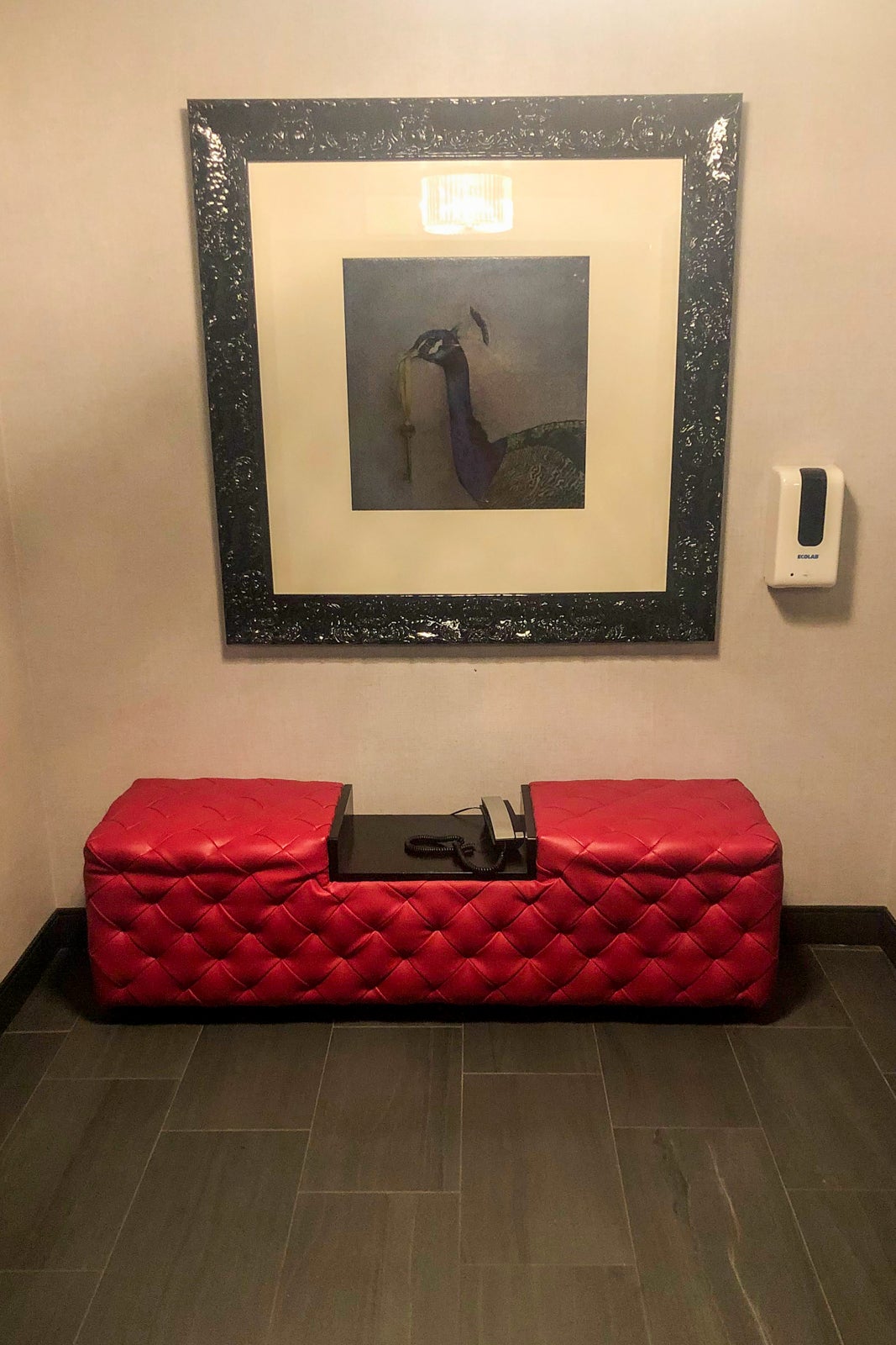 A seating area and photo of a peacock with a key in its mouth. Decor outside of the elevator on the 8th floor of The Clancy hotel.