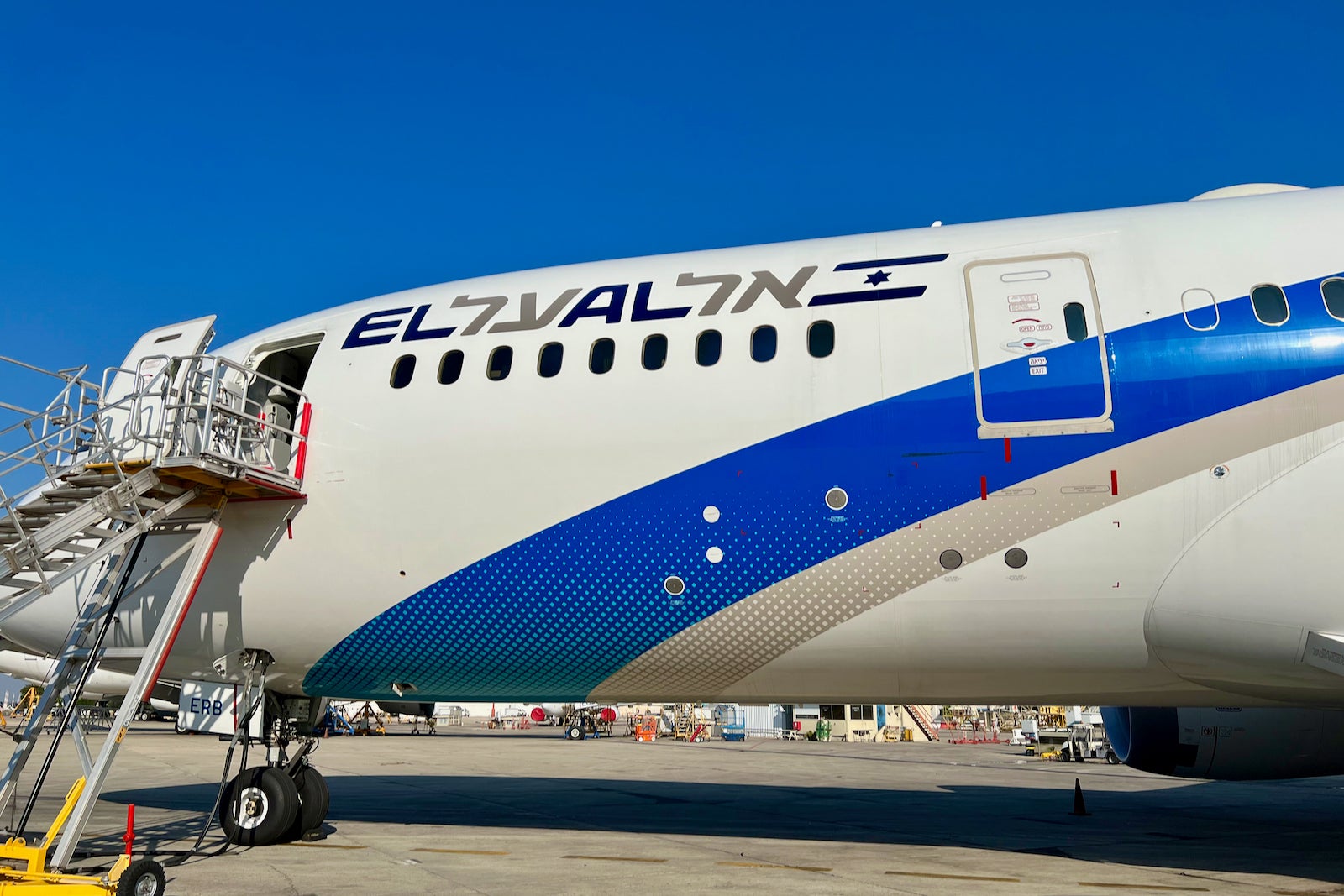 the side of an El Al plane with a ramp to the boarding door