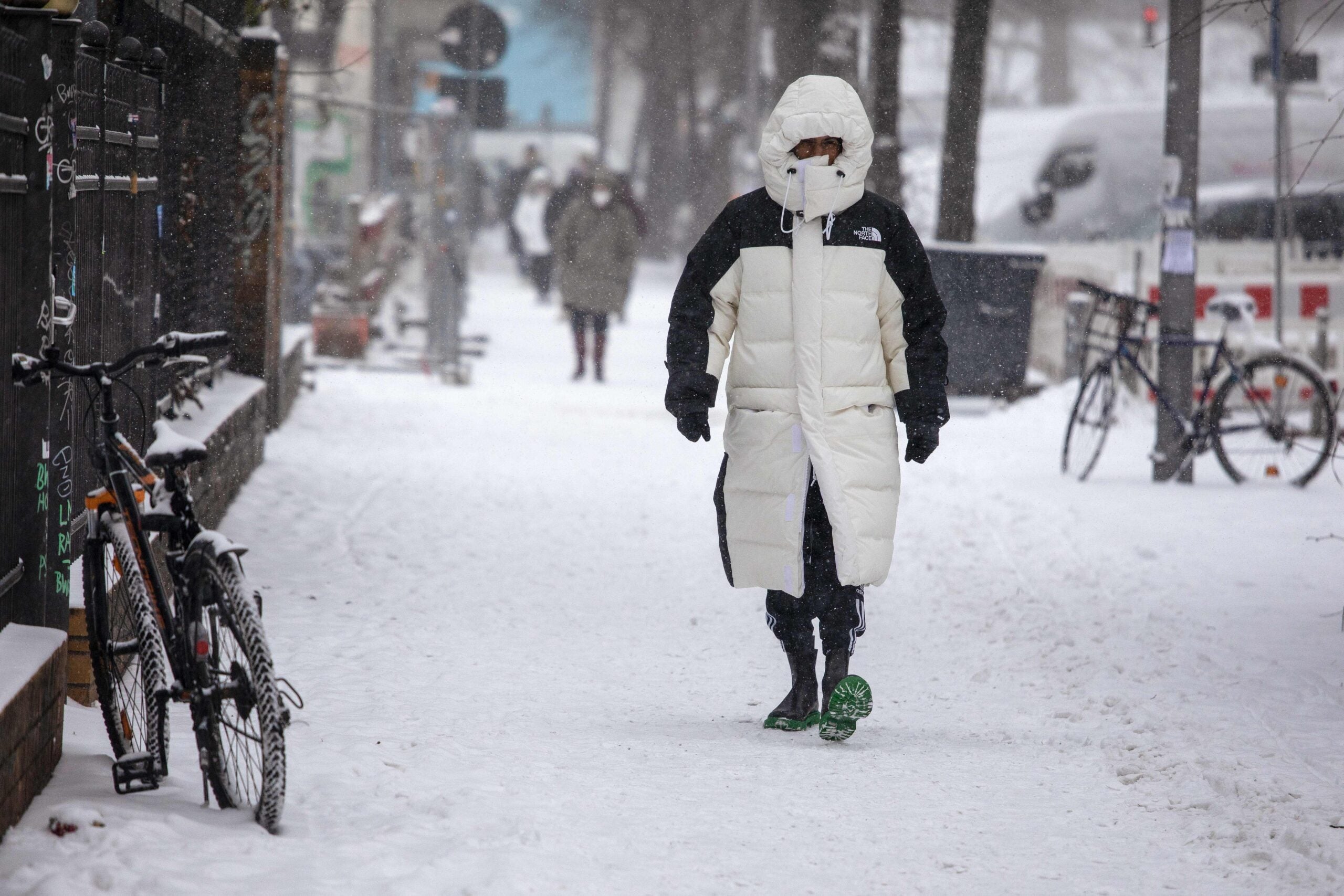 Person in thick parka walks on a sidewalk covered in snow