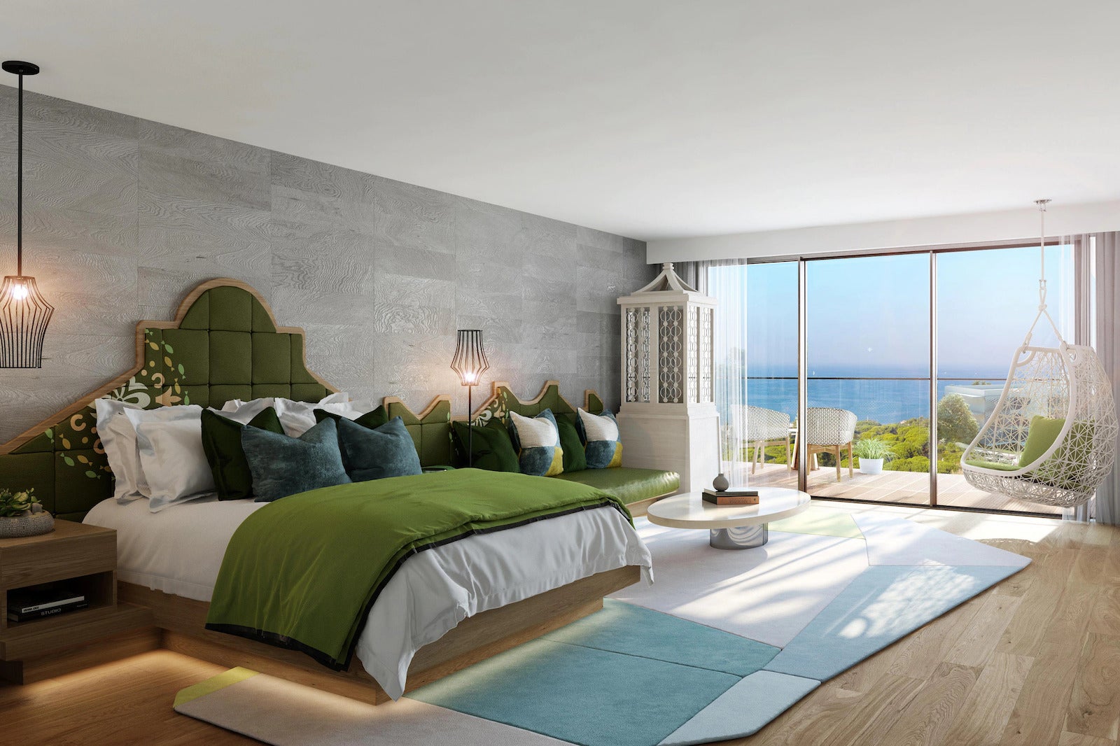 Large open hotel room with bed and green couch looking out at ocean