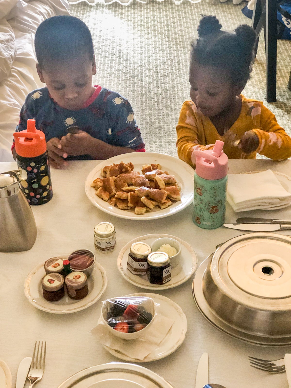 Two children enjoying room service pancakes.