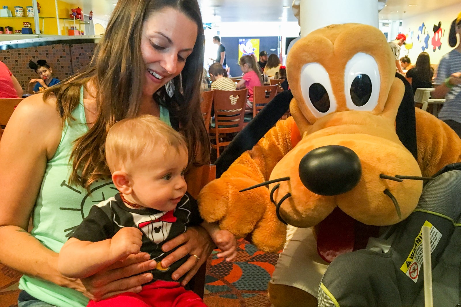 Tarah with her child at a character dining experience with Pluto