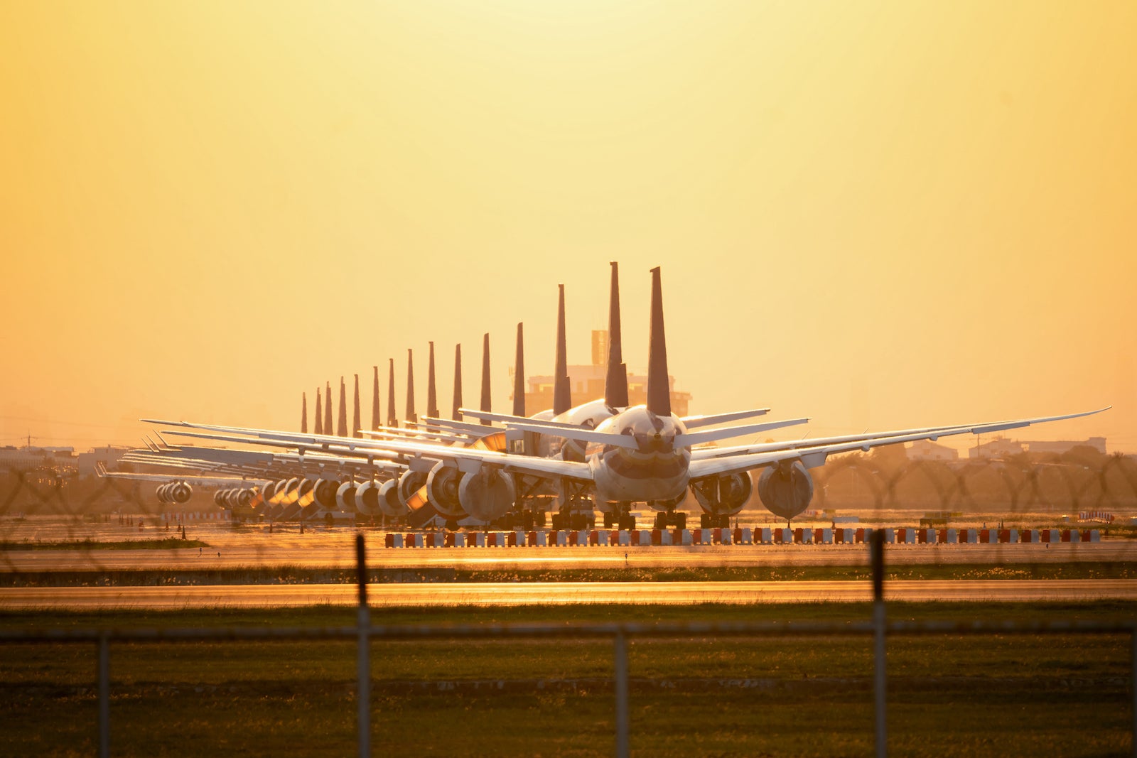 planes in line on a runway at sunset