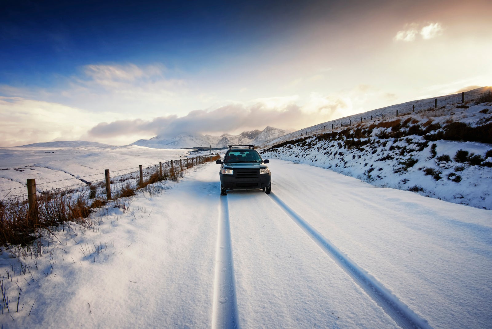 UK, Scotland, Isle of Skye, Cuillin Mountains, four wheel drive vehicle driving on snow-covered street