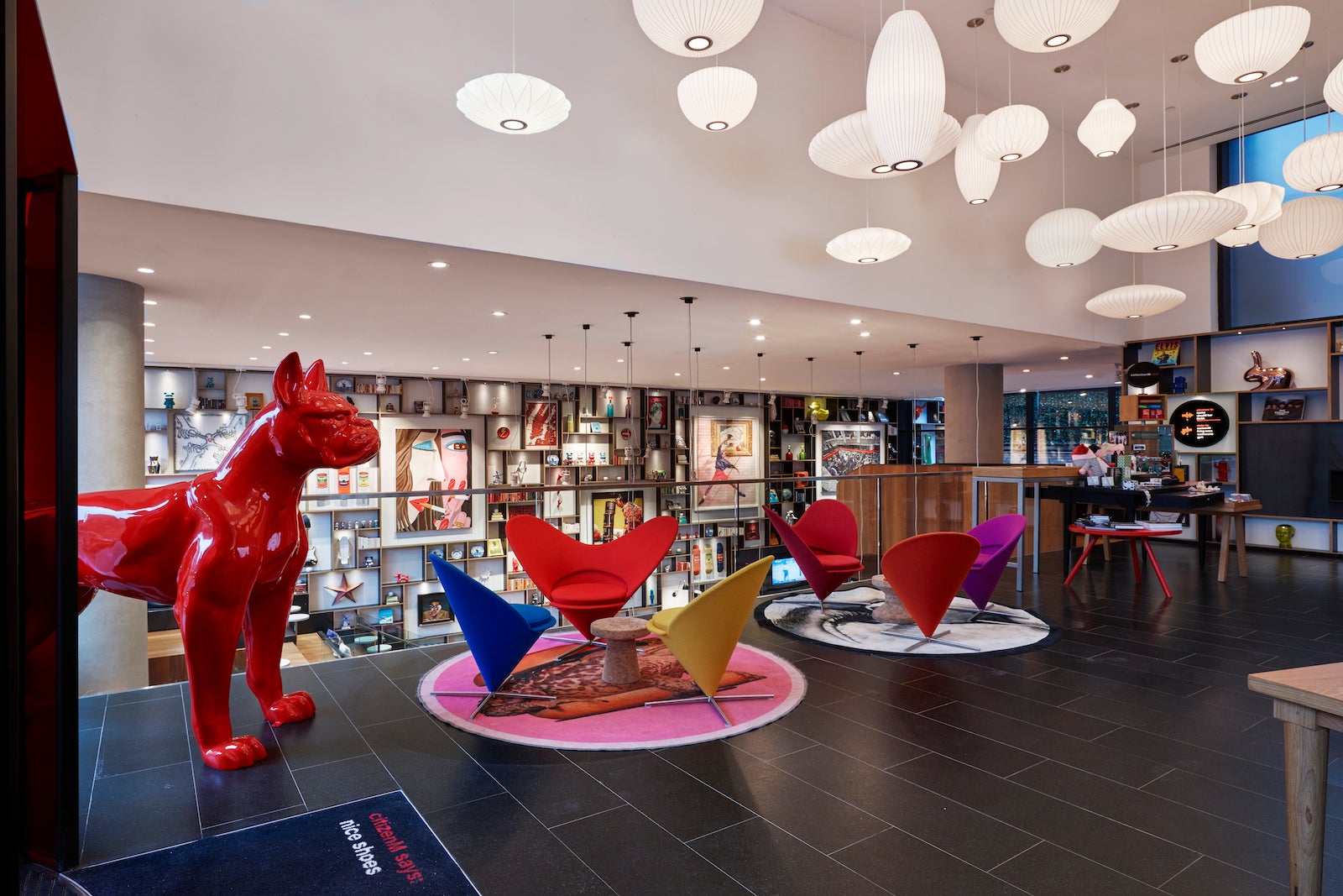 wall full of art, colorful chairs shaped like hearts and large red statue of dog