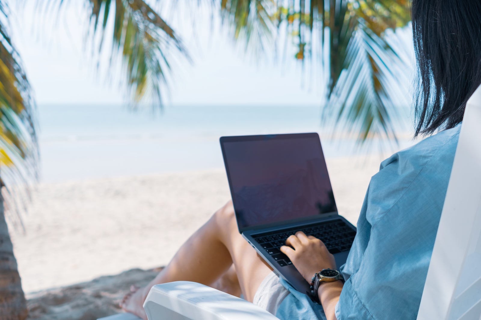 woman sitting in chair on beach working on laptop