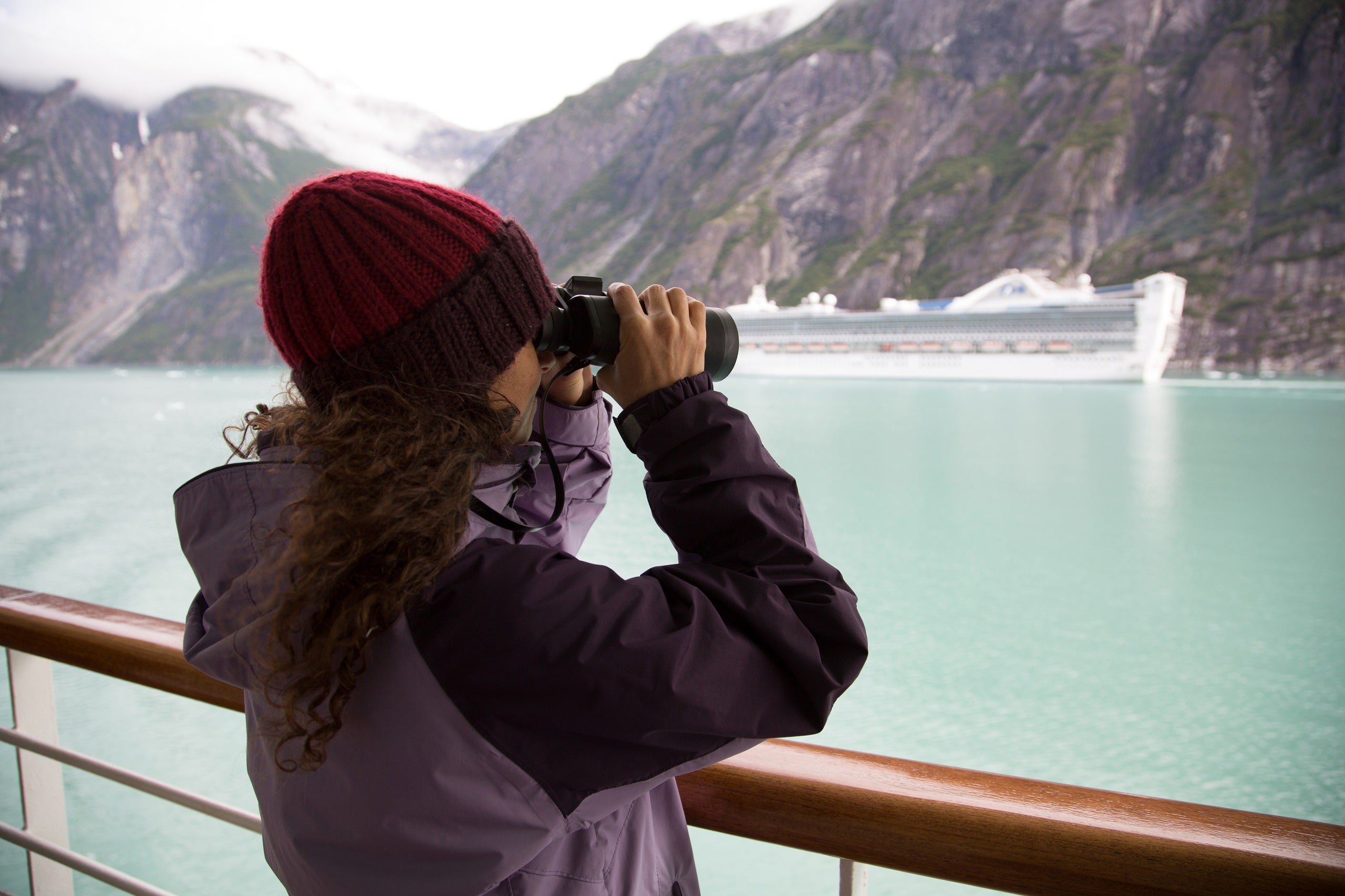 Woman using binoculars on cruise ship, Ketchikan, Alaska, USA