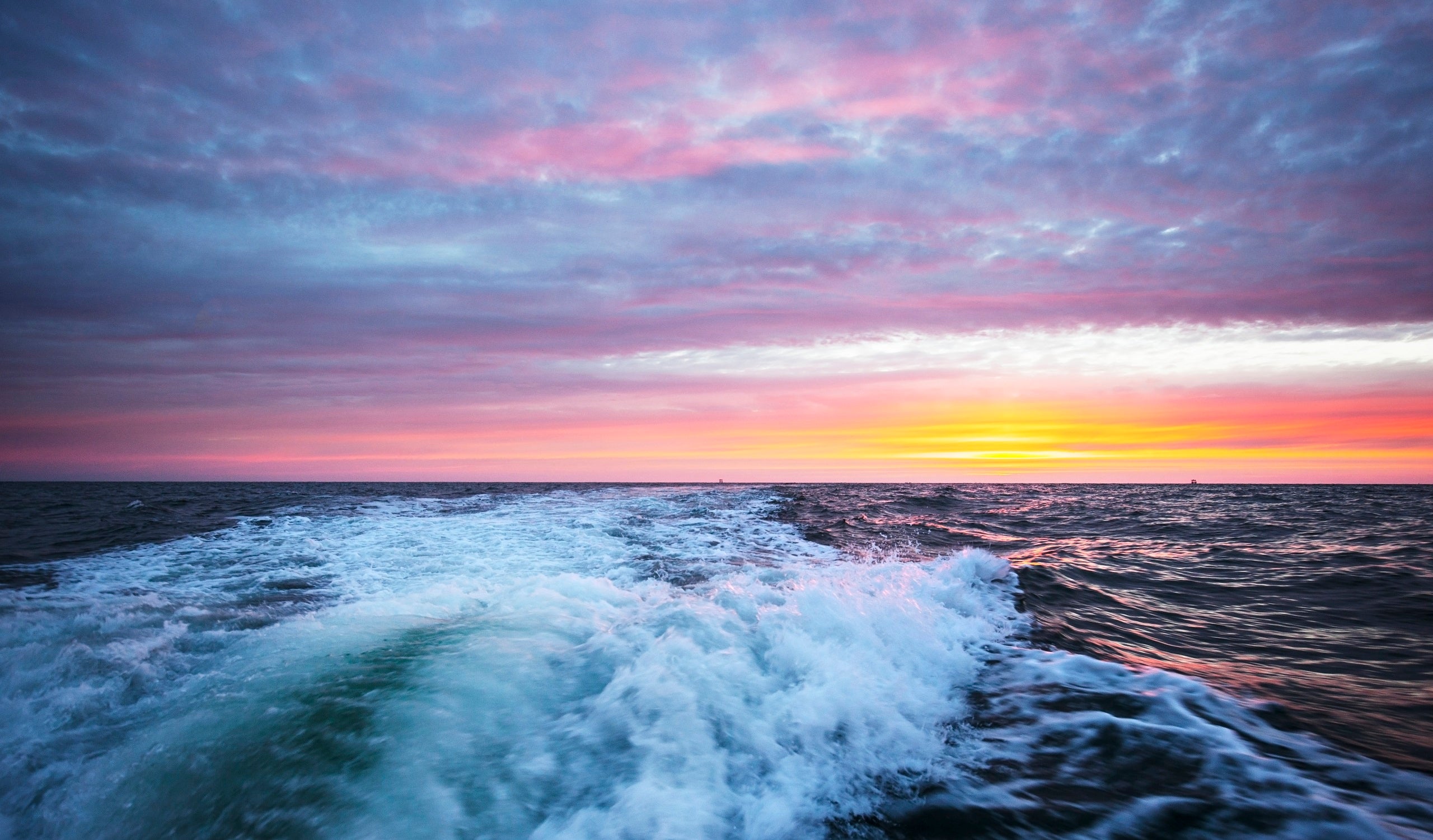 A wake of a motorboat at sunset time