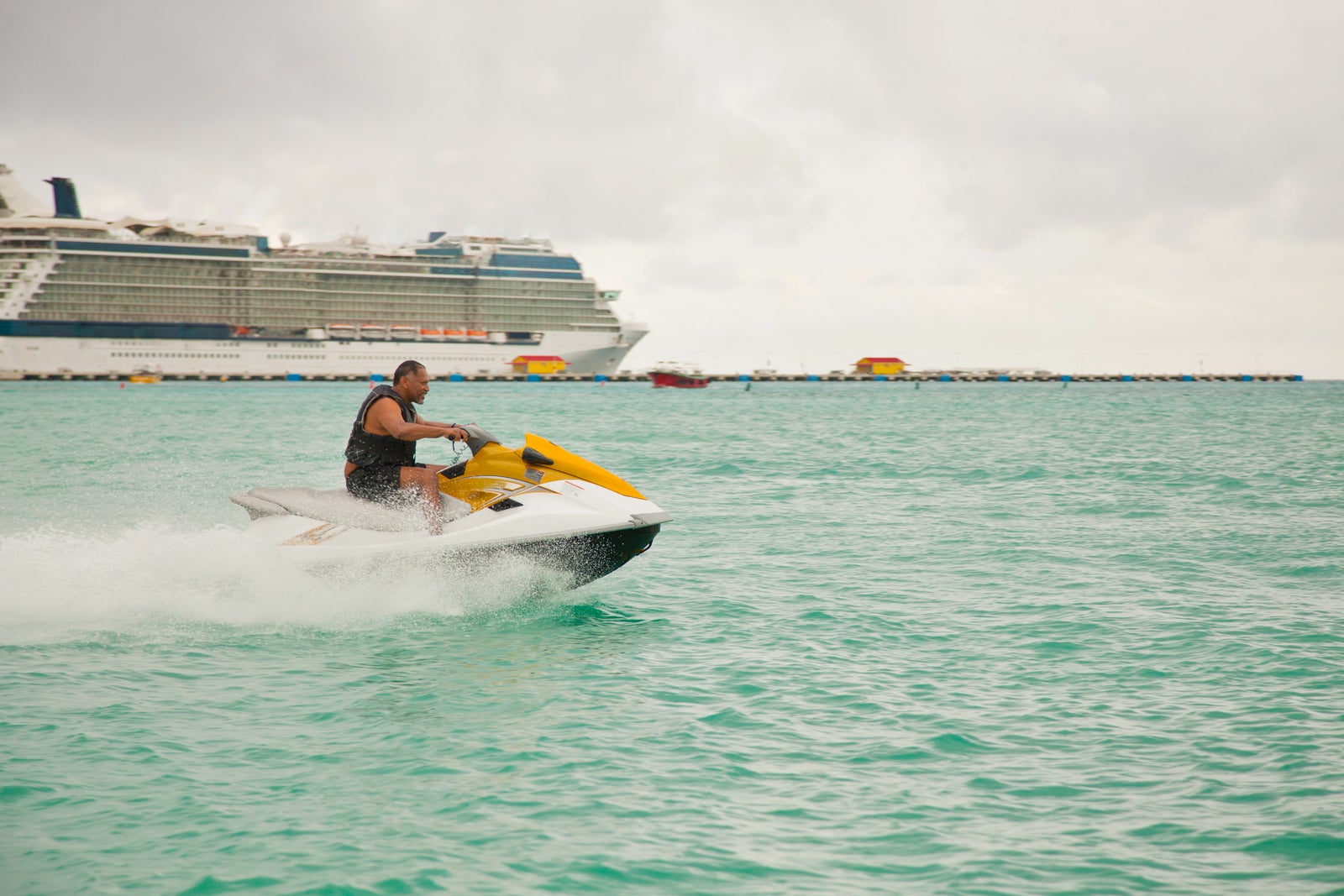 Man riding jet ski in front of cruise ship