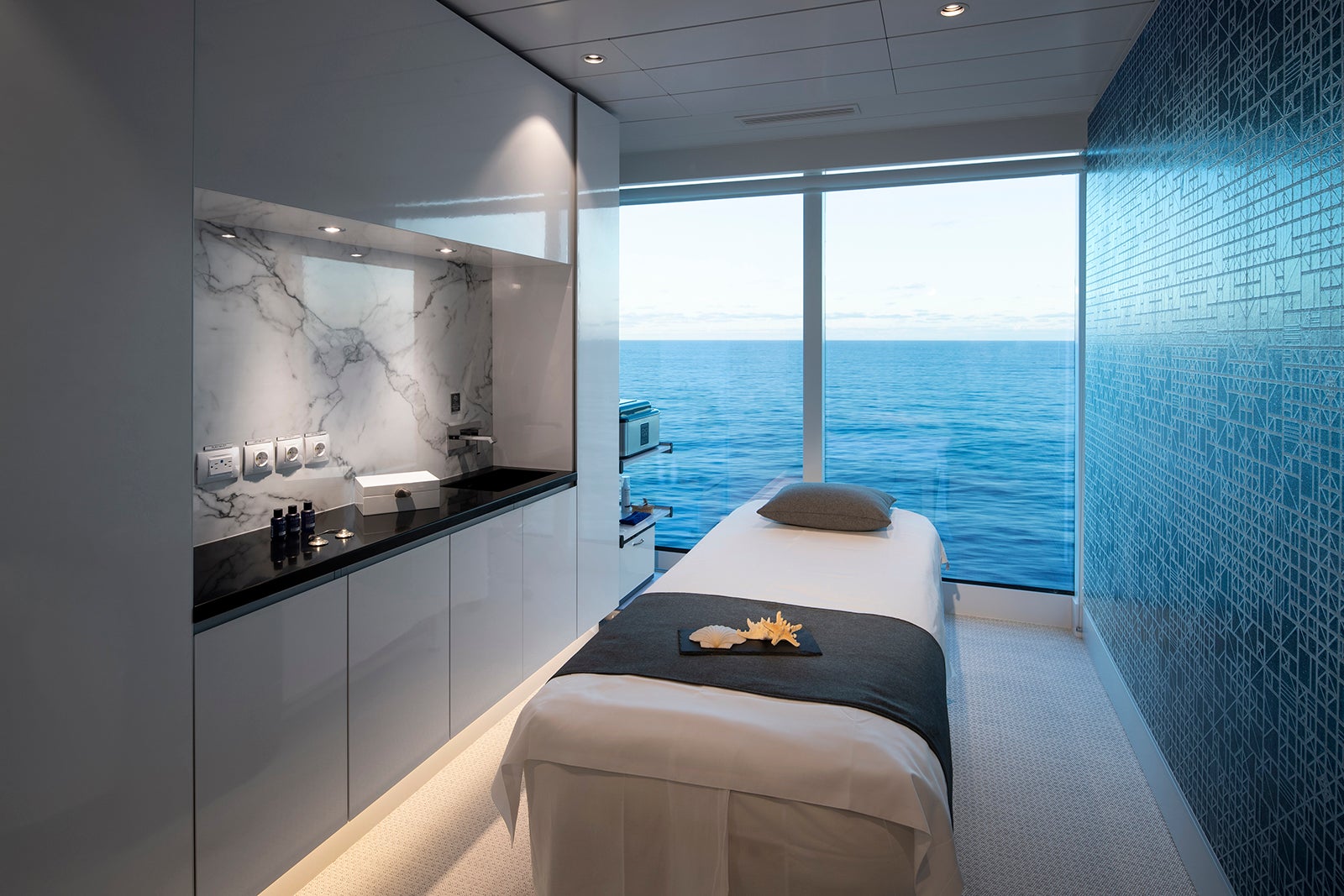 Massage bed facing window with ocean view in cruise ship spa treatment room.