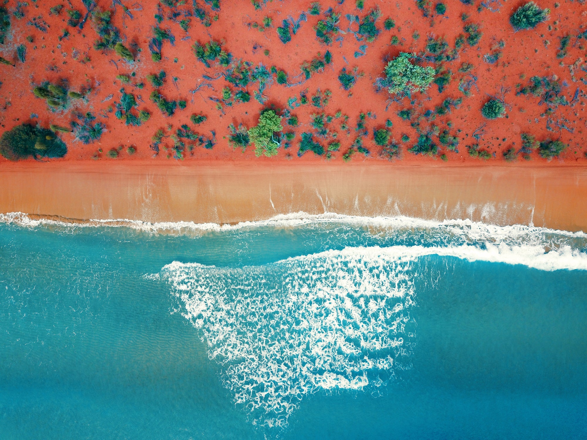 Aerial top view of a bright orange sandy beach in Western Australia
