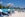 Crowded beach with chairs and umbrellas with cruise ship in the background